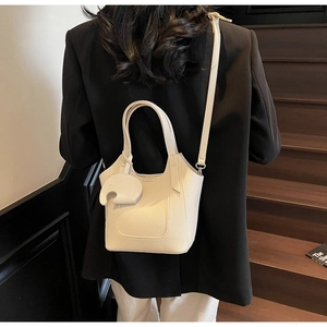 Cream lychee texture bucket bag with elephant charm shown on a casual black blazer outfit