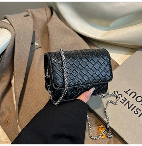 Close-up of classic black woven texture mini bag with elegant silver chain strap