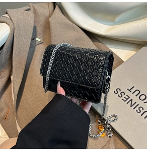 Close-up of a small black woven texture crossbody bag with silver chain strap detail