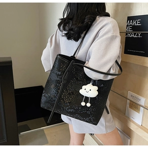 Detailed view of black faux snakeskin tote bag featuring a plush white cloud charm accessory