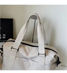 Detalle del asa reforzada y tejido de nailon duradero en el bolso de viaje blanco roto