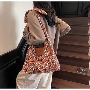 Detail van bloemen canvas shopper met oranje print en een bruine lederen gesp sluiting
