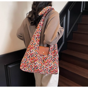 Detail van bloemen canvas shopper met bruine leren flap en gouden magnetische gespsluiting