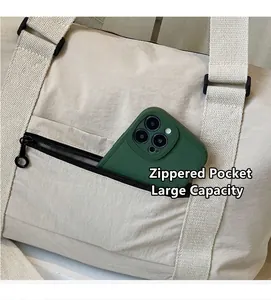 Detalle del bolso de viaje blanco crema con bolsillo con cremallera y móvil de escala