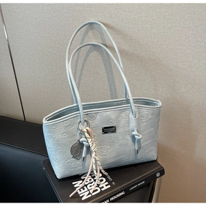 Light blue tote bag detail featuring bear embossing and a decorative tennis racket charm