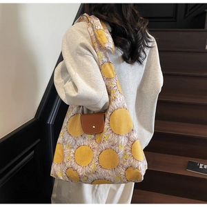Detail van canvas tas met zonnebloemprint, bruine lederen flap en metalen sluiting