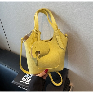 Detail of yellow litchi pattern leather handbag with matching elephant charm and strap