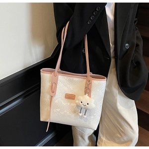 Close-up of a white tote bag with snake texture and a cute cloud charm on a model