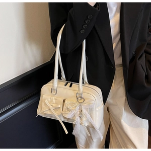 Detail view of cream PU leather shoulder bag with bow pockets on a model in a black suit