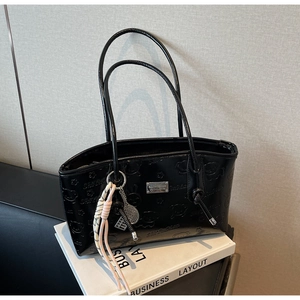 Detail of black patent leather tote with cartoon embossed patterns and unique charm