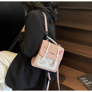 Detail eines rosa-cremefarbenen Rucksacks mit Cartoon-Stickerei und Herzmustern am Modell