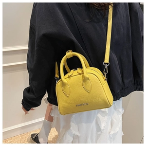 Detail view of mini yellow litchi pattern leather boston bag shown on a model