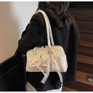 Detailed close-up of cream glossy shoulder bag featuring lace pearl charm and utility pockets