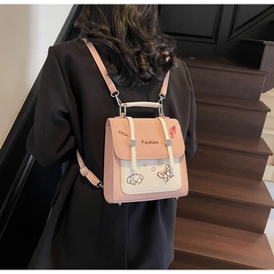 Detail eines rosa-beigen Rucksacks mit niedlicher Cartoon-Stickerei, präsentiert am Model