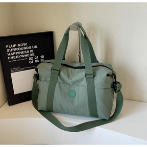 Detail of light green nylon travel bag featuring reinforced handles and a round logo