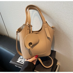 Detailed view of camel leather bucket bag with elephant pendant and pebble grain texture