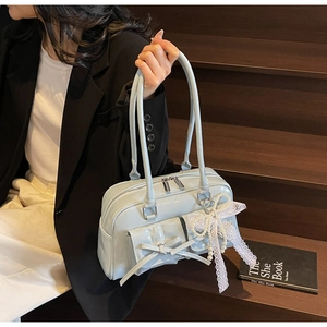 Detail of light blue patent leather bag with bow accents and pearl lace charm accessory