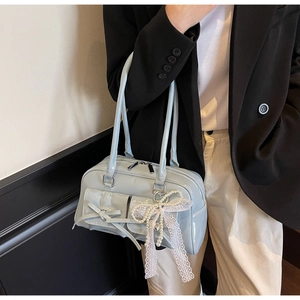 Detail of light blue faux leather bag with bow pockets and pearl lace pendant charm