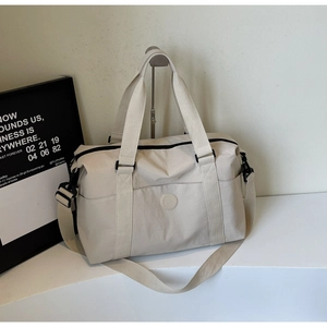 Detail of beige travel bag showing waterproof nylon texture and adjustable shoulder strap