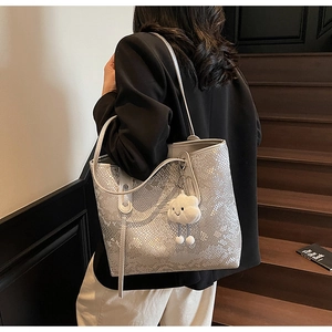 Detail of silver python texture tote bag with a white plush cloud charm and dual handles