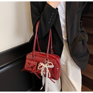 Close-up of red patent leather bowling bag featuring bow pockets and pearl heart charm