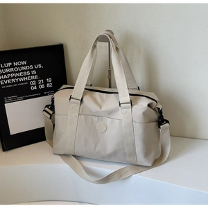 Detail of beige nylon travel tote bag showing adjustable strap and circular logo