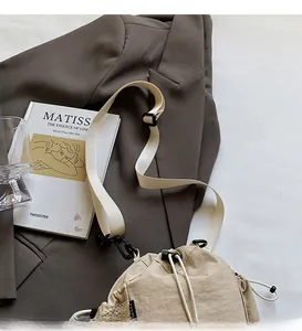 Details des verstellbaren Riemens und Kordelzugs einer beige Nylon-Eimertasche