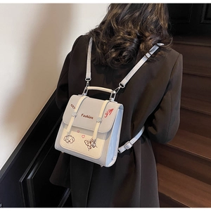 Nahaufnahme eines Mini-Patchwork-Rucksacks mit Stickerei an einem Model in schwarzem Blazer