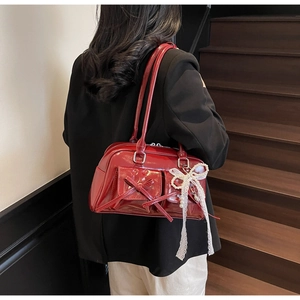 Detail view of burgundy patent leather bag with bow pockets and lace pearl charm