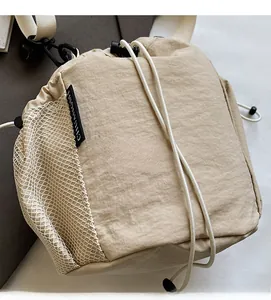 Detail der beigen Nylon-Beuteltasche mit seitlicher Netztasche und verstellbarem Gurt