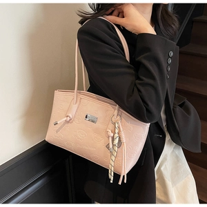 Detail of pink embossed tote bag with teddy bear pattern and decorative silk scarf accessory