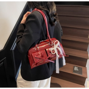 Detail of red patent leather shoulder bag with decorative bows and pearl lace charm