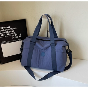 Close-up of durable navy nylon travel tote with circular logo and adjustable strap