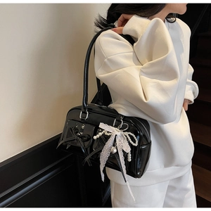 Detailed shot of black patent leather bowling bag with lace bows and pearl charms