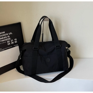 Close-up of durable black nylon travel tote featuring a round logo and adjustable strap