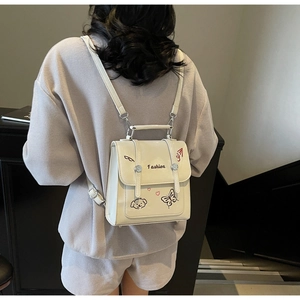 Detail des cremefarbenen PU-Lederrucksacks mit Cartoon-Illustrationen am Modell