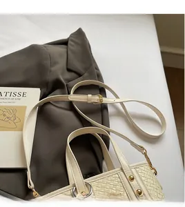 Detail of cream woven tote bag showing golden metal buckle and adjustable shoulder strap