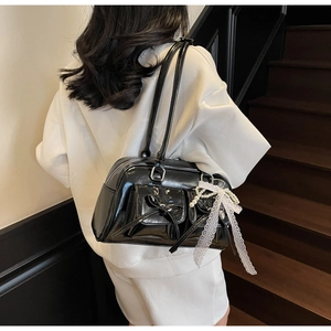 Detail of black patent leather bag featuring bow pockets and pearl lace charms