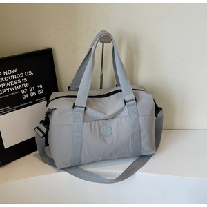 Close-up of light grey travel tote featuring reinforced handles and adjustable shoulder strap