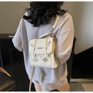 Detail eines schicken cremefarbenen PU-Lederrucksacks mit Cartoon-Print am Modell