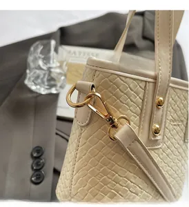 Close-up of cream woven bucket bag featuring polished gold hardware and D-ring detail
