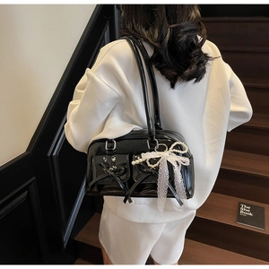 Detail view of black patent leather shoulder bag with lace pearls and bow decoration