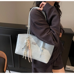 Detail of light blue hobo bag with embossed bear patterns and woven rope accessory