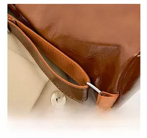 Dettaglio degli anelli in metallo argentato e cuciture su borsa in pelle marrone