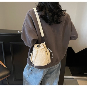 Detailansicht der beigen Tunnelzug-Beuteltasche mit Netztasche und breitem Gurt