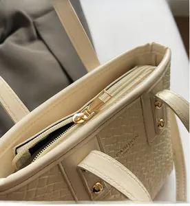 Close-up of smooth gold metal zipper and woven texture on a cream bucket bag