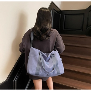 Light purple large capacity tote bag shown with shoulder strap on a person in lifestyle setting