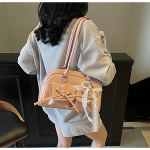 Detail of pink patent leather handbag featuring delicate lace bows and pearl charms