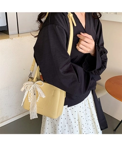 Elegante borsa a secchiello gialla con fiocco in pizzo e ciondolo di perle su modella
