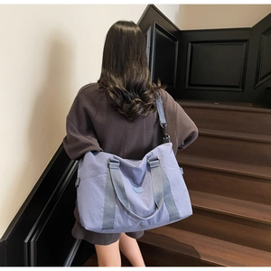 Rear view of a lilac travel tote bag with grey straps used on outdoor stairs